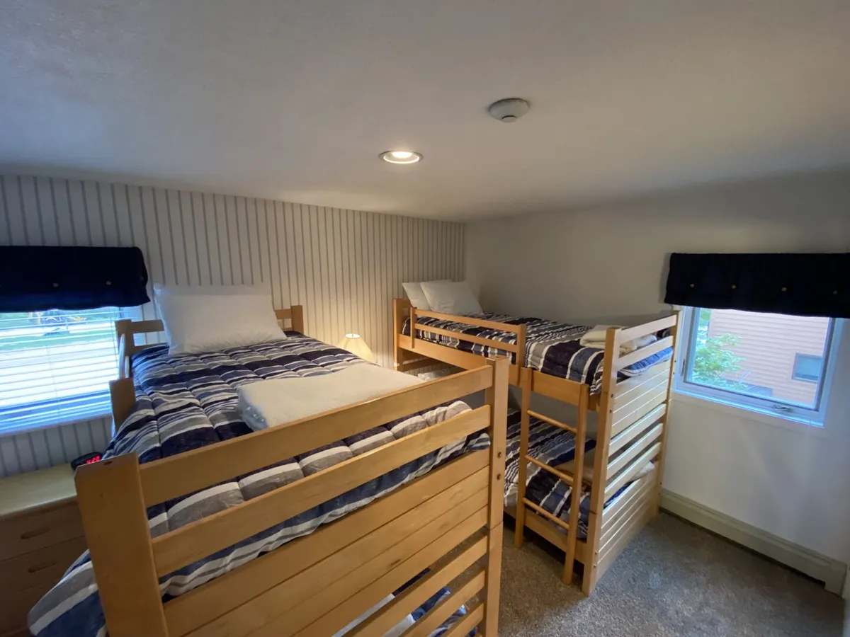 This interior shot captures a set of cozy bunk beds with striped bedding and a window with blinds, creating a comfortable, playful nook perfect for kids. The space feels inviting and practical for family stays, reflecting the home’s family-oriented design.