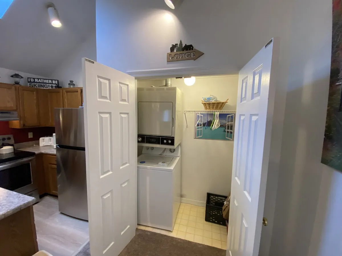 Practical kitchen area featuring a washer and dryer, kitchen appliances, and a friendly atmosphere that blends convenience with social space. A small sign adds a homey touch.
