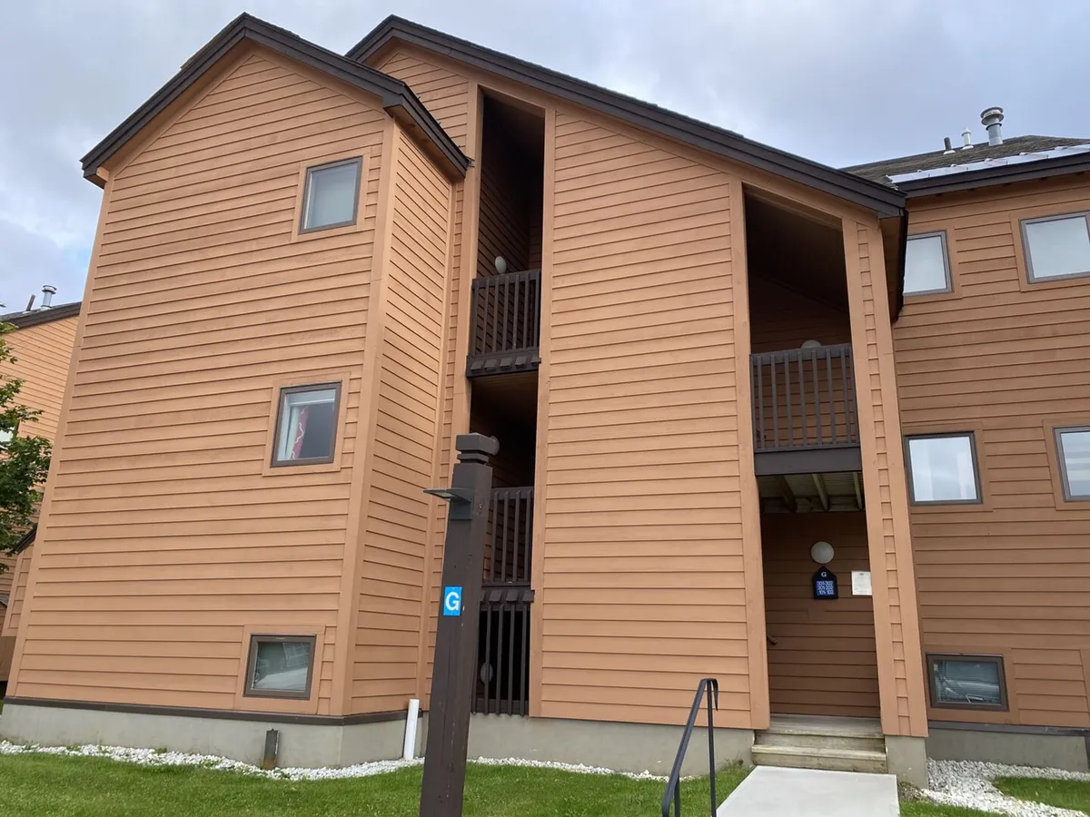 The photo features the condo’s wooden siding, balconies, and entrance steps, suggesting a relaxed, communal atmosphere. It hints at opportunities for families to gather, relax outdoors, and enjoy views of the surrounding landscape after a day on the mountain.