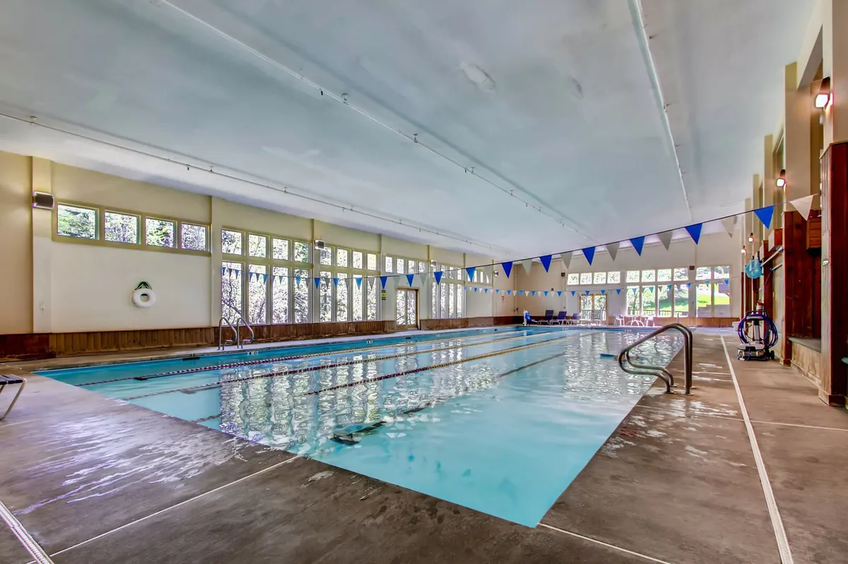 This image features the resort's spacious indoor swimming pool, with inviting blue water, large windows that let in natural light, and festive pennant flags overhead. The pool area is clean and well-lit, suggesting a relaxing and refreshing environment suitable for both exercise and leisure.